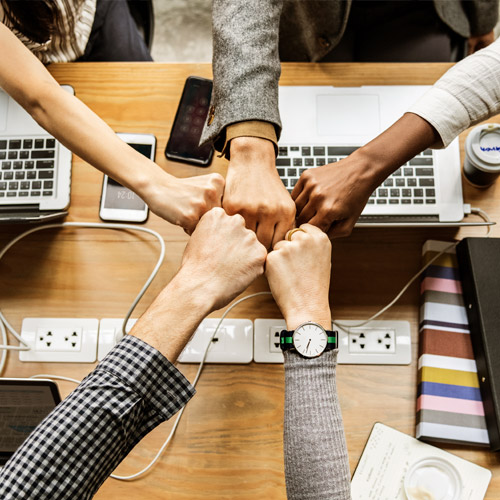 Diverse hands in a fist bump over a desk