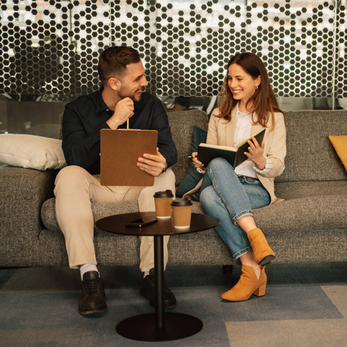 Two professionals collaborating on a couch, suggesting teamwork-oriented current job openings
